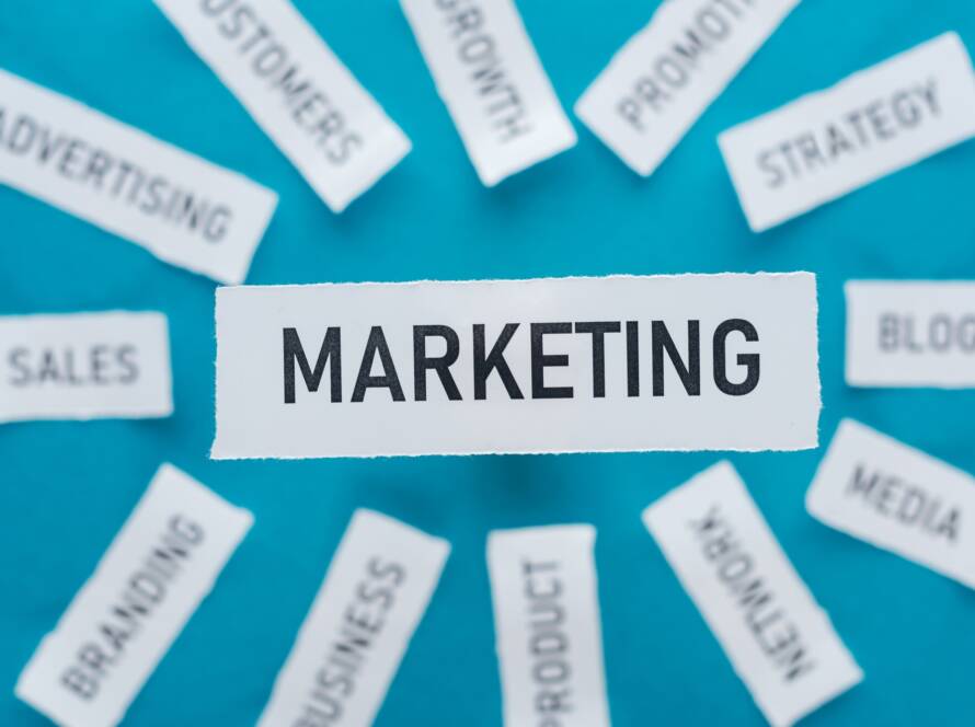 selective focus of word marketing and components related to marketing on pieces of paper on blue